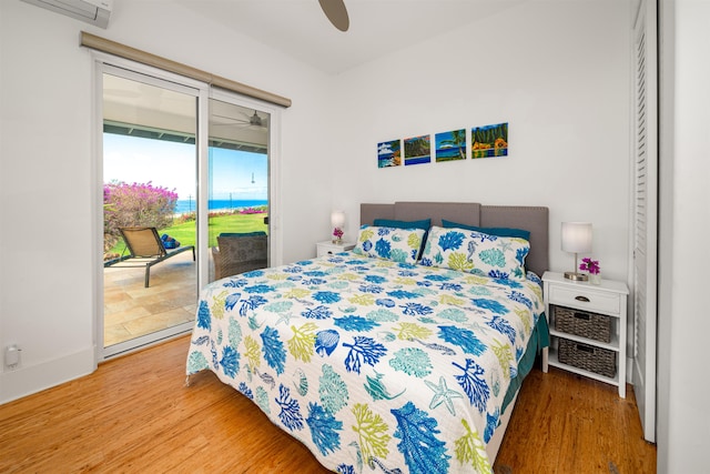 bedroom featuring hardwood / wood-style floors, ceiling fan, access to exterior, and a wall mounted AC