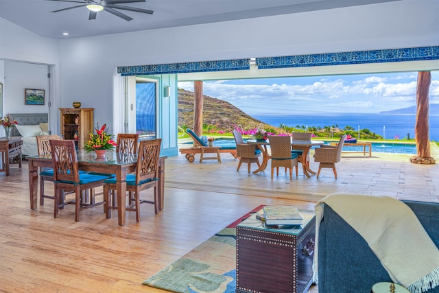 dining room featuring ceiling fan, light hardwood / wood-style floors, and a water and mountain view