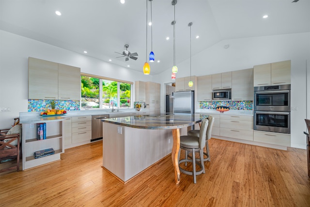 kitchen with light wood-type flooring, stainless steel appliances, a kitchen island, and ceiling fan