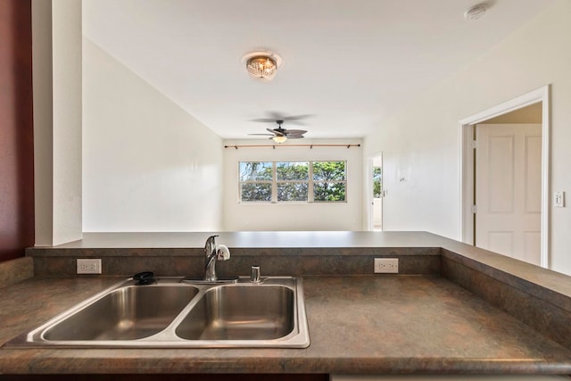 kitchen with dark countertops, a ceiling fan, and a sink