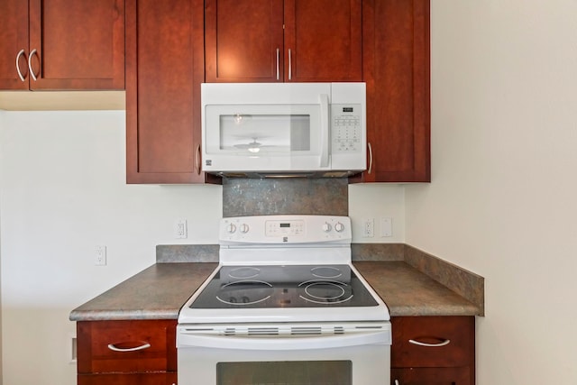 kitchen with dark countertops, white appliances, and backsplash