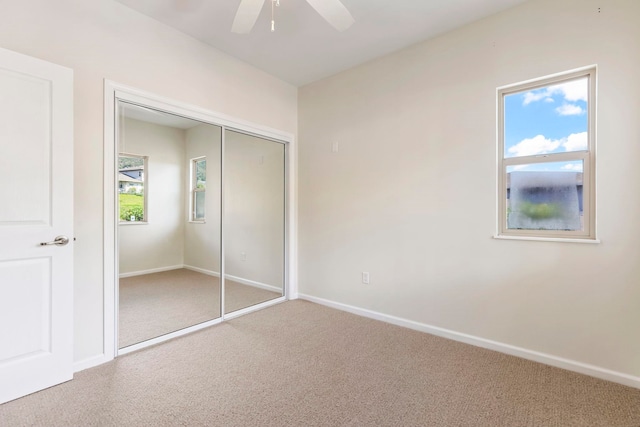 unfurnished bedroom featuring baseboards, a ceiling fan, carpet floors, and a closet