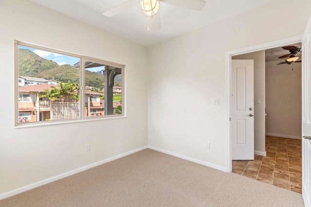 carpeted empty room featuring ceiling fan and baseboards