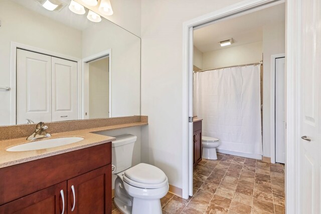 full bath featuring stone finish floor, toilet, vanity, baseboards, and curtained shower