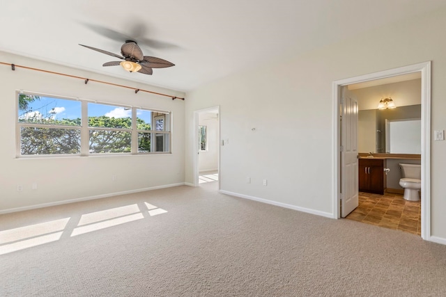 interior space with ceiling fan, baseboards, carpet floors, and ensuite bath