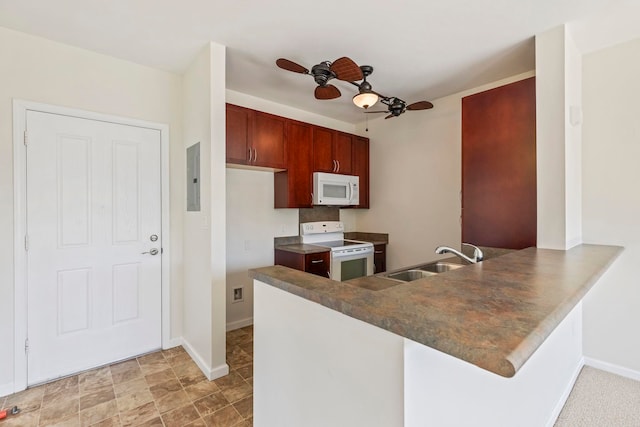 kitchen featuring a sink, white appliances, a peninsula, baseboards, and dark countertops