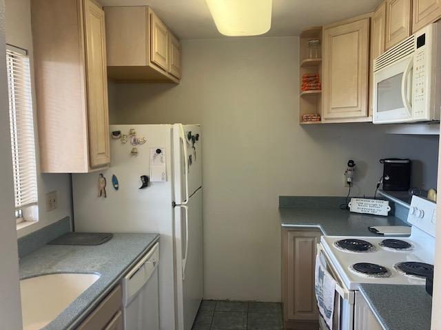 kitchen with tile patterned floors, light brown cabinetry, a sink, open shelves, and white appliances