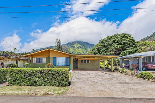 single story home with a carport, concrete block siding, a mountain view, and driveway