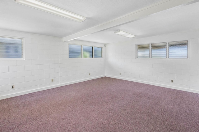 unfurnished room featuring carpet floors, concrete block wall, and beamed ceiling