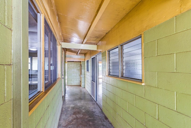 corridor with concrete block wall and unfinished concrete flooring