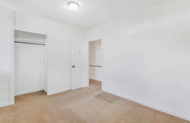 unfurnished bedroom with a closet and light colored carpet