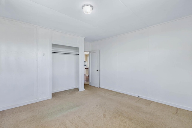 unfurnished bedroom featuring light carpet, a closet, and baseboards