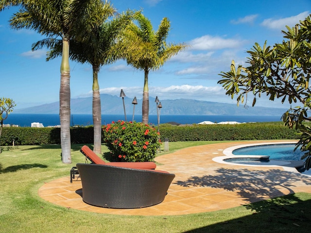 exterior space with a patio area, a water and mountain view, a lawn, and an in ground hot tub