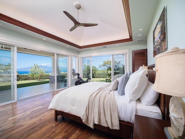 bedroom featuring dark hardwood / wood-style flooring, access to exterior, a raised ceiling, and ceiling fan