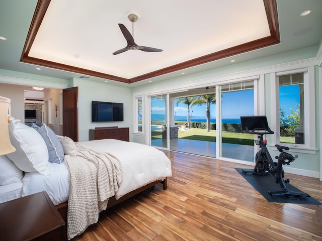 bedroom with hardwood / wood-style flooring, ceiling fan, a tray ceiling, and access to outside