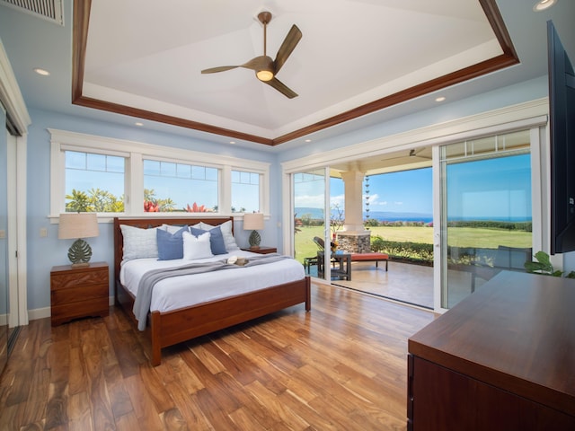 bedroom featuring a tray ceiling, access to outside, ceiling fan, and hardwood / wood-style flooring