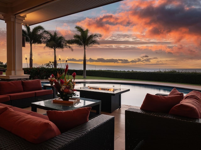 patio terrace at dusk featuring a water view and an outdoor living space with a fire pit