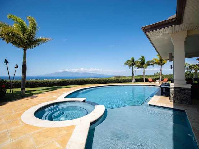 view of swimming pool featuring a mountain view, a patio, and an in ground hot tub