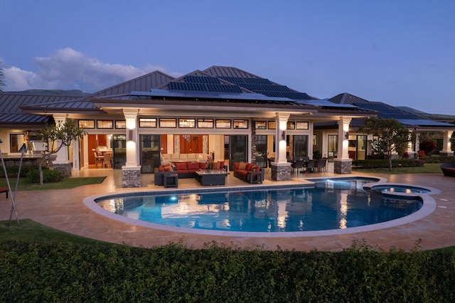 pool at dusk with an outdoor living space, a patio area, and an in ground hot tub