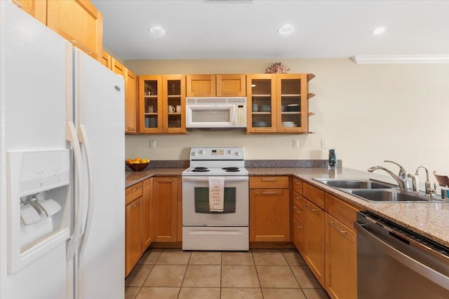 kitchen with sink, white appliances, light stone countertops, and light tile patterned floors