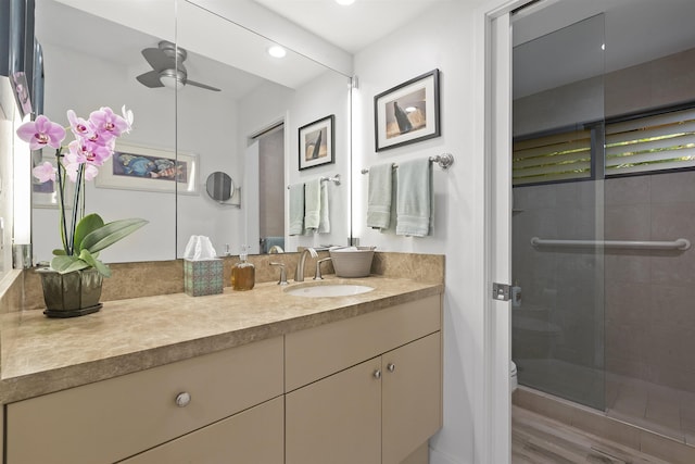 bathroom with recessed lighting, toilet, a ceiling fan, a shower stall, and vanity