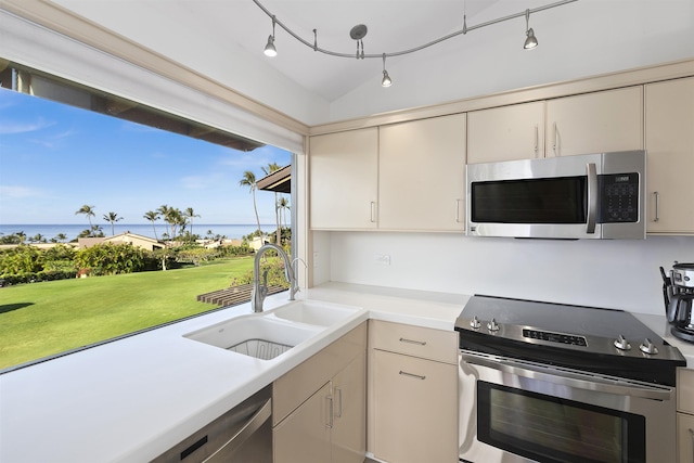 kitchen with cream cabinets, a water view, a sink, light countertops, and appliances with stainless steel finishes