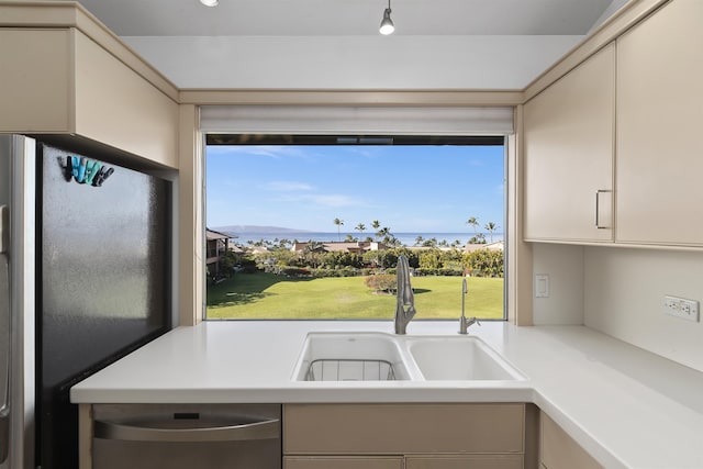 kitchen featuring cream cabinets, stainless steel appliances, light countertops, and a sink