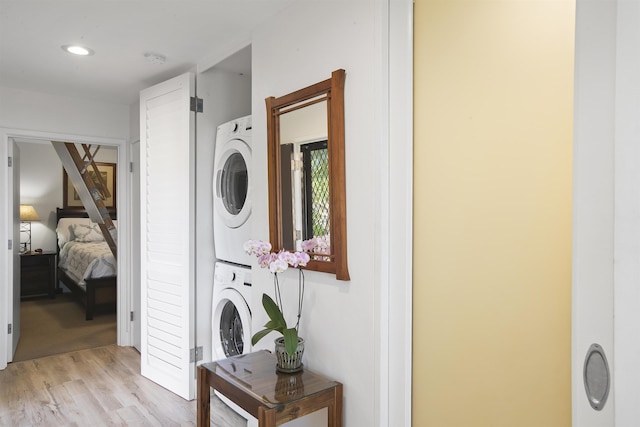 laundry room featuring light wood-type flooring, laundry area, and stacked washing maching and dryer