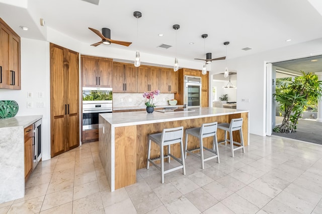 kitchen with a spacious island, hanging light fixtures, a healthy amount of sunlight, and ceiling fan