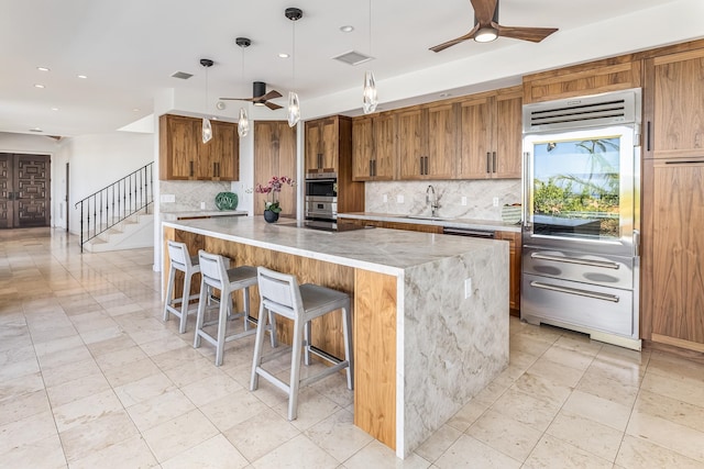 kitchen featuring pendant lighting, a kitchen breakfast bar, ceiling fan, and a spacious island