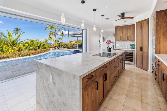 kitchen featuring a large island, pendant lighting, beverage cooler, black electric cooktop, and ceiling fan