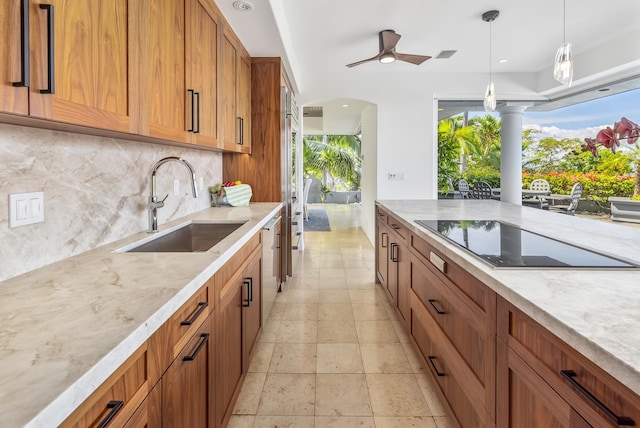 kitchen with pendant lighting, black electric stovetop, tasteful backsplash, sink, and ceiling fan