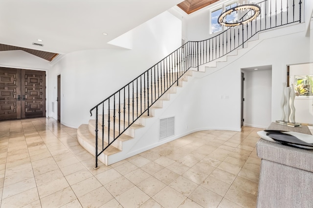 stairway with a notable chandelier and high vaulted ceiling