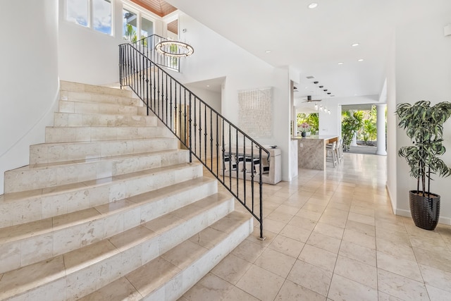 stairs with a notable chandelier, tile patterned floors, and plenty of natural light