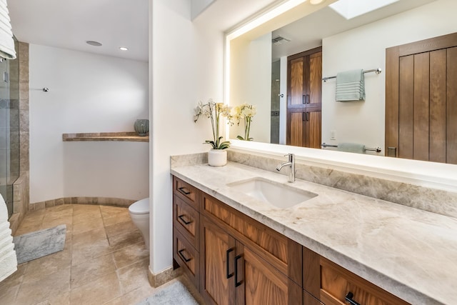 bathroom featuring vanity, toilet, a skylight, and a shower with shower door