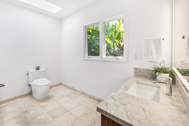 bathroom with a skylight, vanity, and toilet