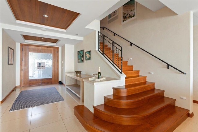 tiled entryway featuring wooden ceiling and a raised ceiling