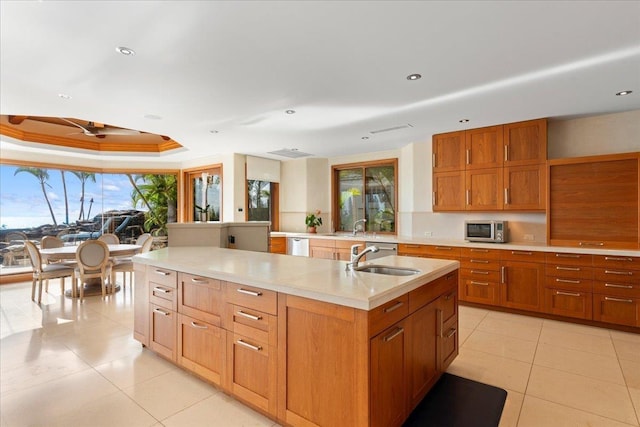 kitchen featuring dishwasher, an island with sink, sink, a raised ceiling, and light tile patterned flooring