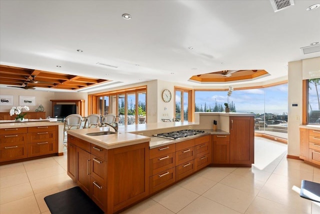 kitchen featuring sink, a tray ceiling, stainless steel gas stovetop, and plenty of natural light