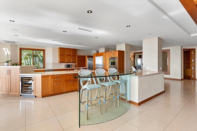 kitchen featuring light tile patterned floors, appliances with stainless steel finishes, beverage cooler, and a large island