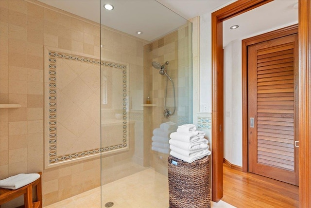 bathroom featuring a tile shower, wood-type flooring, and tile walls