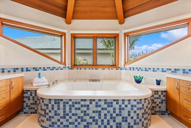 bathroom with tiled bath, tile patterned floors, lofted ceiling with beams, a wealth of natural light, and wooden ceiling