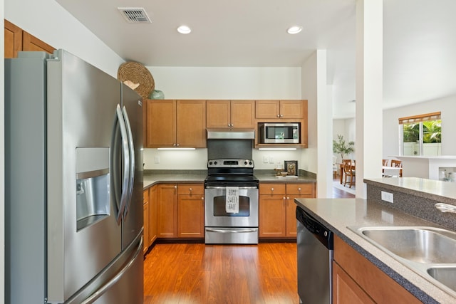 124 Kapela Pl, Kahului, HI 96732 - kitchen with under cabinet range hood, appliances with stainless steel finishes, brown cabinetry, and a sink