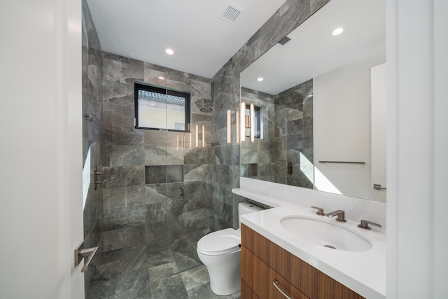 bathroom with tiled shower, vanity, and toilet