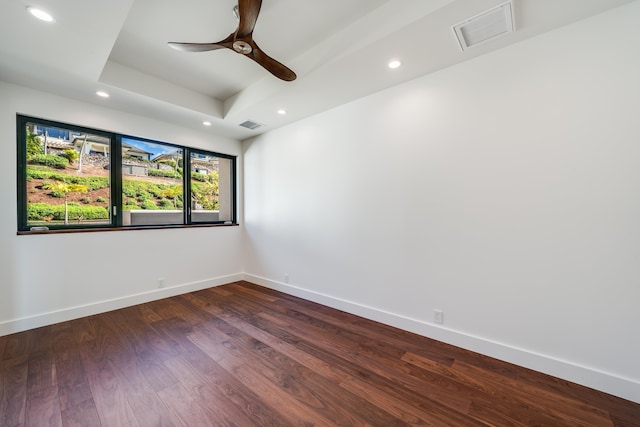 empty room featuring dark wood-type flooring, a raised ceiling, and ceiling fan