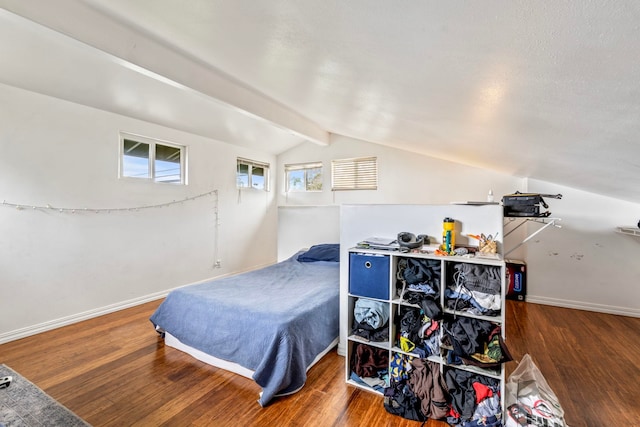 bedroom with wood-type flooring, a textured ceiling, and vaulted ceiling with beams