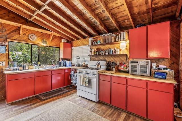 kitchen featuring wood walls, light wood-type flooring, vaulted ceiling with beams, white gas stove, and wood ceiling