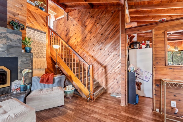 living room featuring wooden walls, a fireplace, wooden ceiling, vaulted ceiling with beams, and hardwood / wood-style flooring