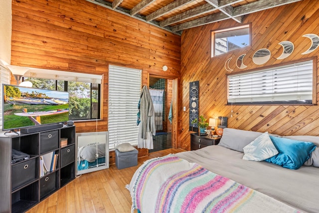 bedroom featuring beamed ceiling, hardwood / wood-style floors, and wood walls