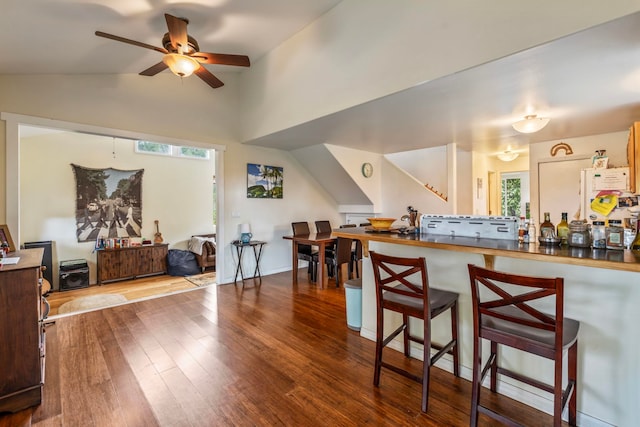 kitchen featuring wood-type flooring, a kitchen breakfast bar, ceiling fan, and lofted ceiling